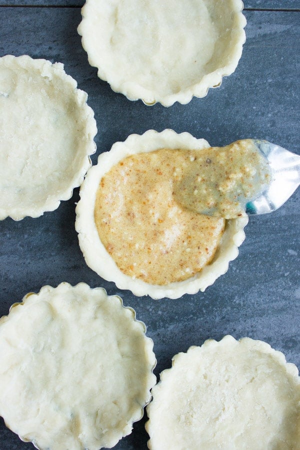 almond frangipane being filled into individual tart shells