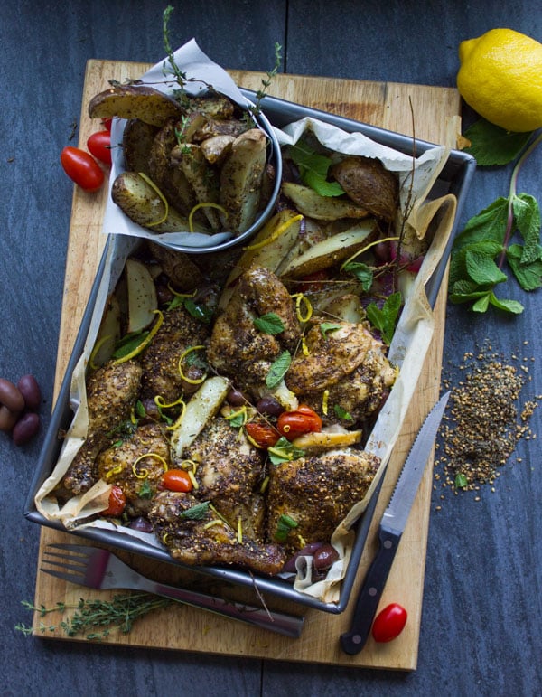 One Pan Chicken Potato Bake With Zaatar on a wooden chopping board with some spices surrounding it