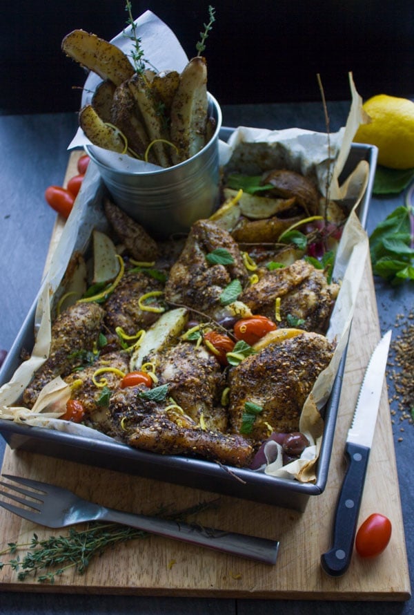 One Pan Chicken Potato Bake With Zaatar on a chopping board with a rustic can filled with potato wedges