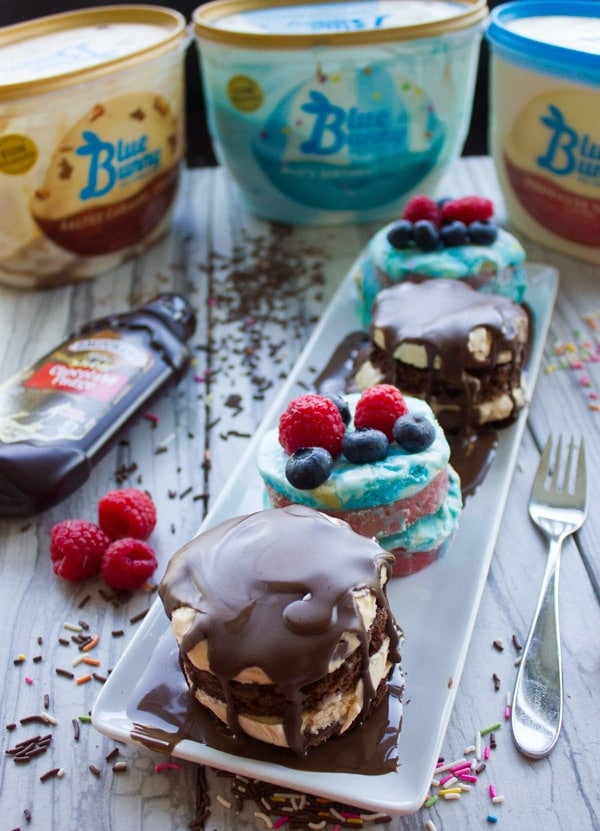 Homemade mini Ice Cream Cakes topped with chocolate sauce and berries on a white plate