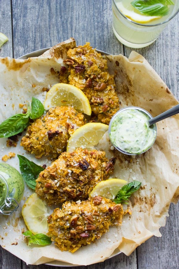 overhead shot of Pecan Crust Baked Chicken Tenders served on parchment paper with a small bowl with basil dip on the side