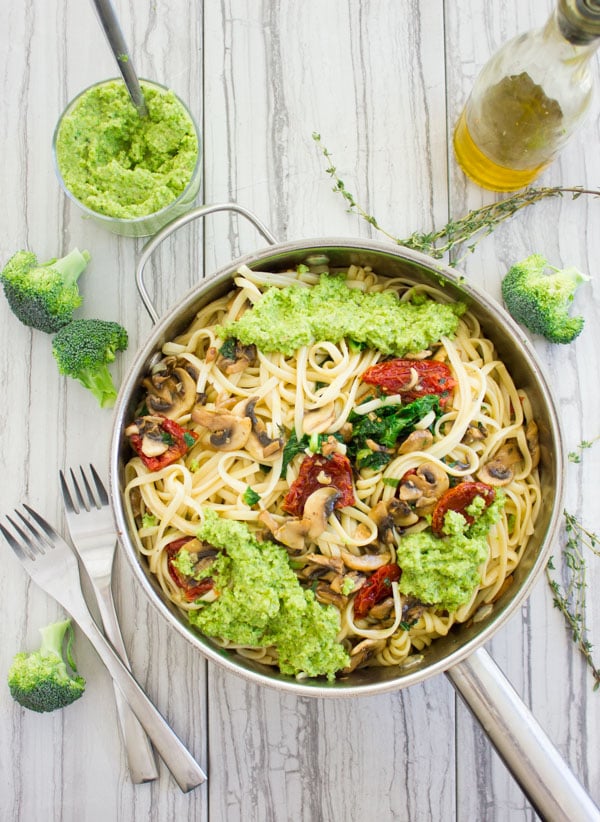 overhead shot of a skillet with mushroom and tomato pasta topped with broccoli pesto