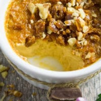 A close up of a ramekin with caramel pudding inside and half of it eaten off showing the creamy texture inside.