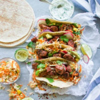 Fiery Tandoori Chicken Tacos with Cilantro Corn Slaw. This is a crazy delicious twist which combines the best of both worlds--succulent tender fiery tandoori chicken pieces on a bed of zesty cilantro corn slaw, topped with radishes, avocados and yogurt sauce, all wrapped in a taco! This recipe is a REAL crowd pleaser in a flash! make it now! www.twopurplefigs.com