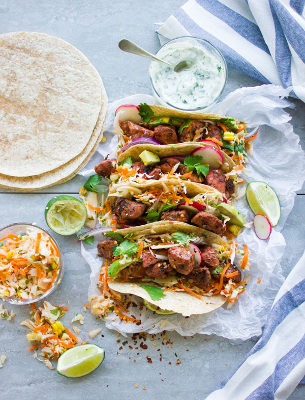 overhead shot of four Tandoori Chicken Tacos with Cilantro Corn Slaw and fresh tortillas on the side