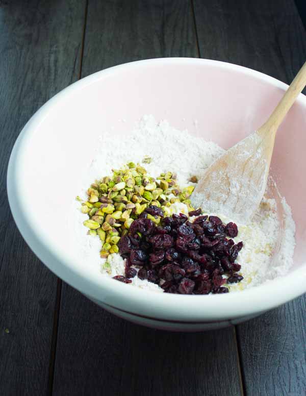 cranberries and pistachios being added to a biscotti batter
