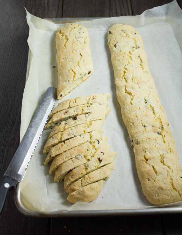 pistachio and cranberry biscotti being cut from a log of pre-baked batter