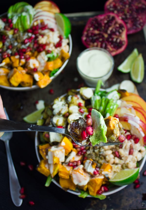 a fork being balanced over a Lentil Fall Harvest Buddha Bowl with roasted brussels sprouts, sweet potatoes and pomegranate seeds