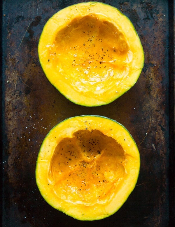 a halved kabocha squash on a baking sheet cut side up