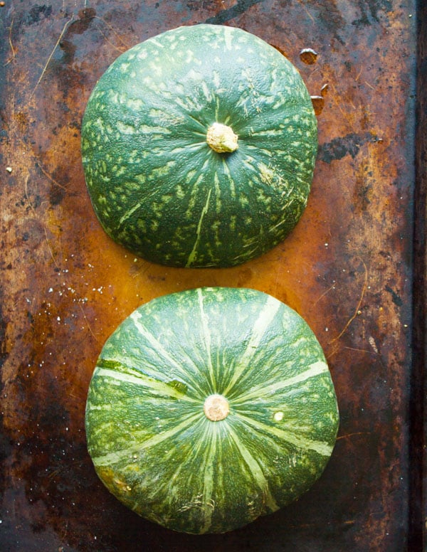 a halved kabocha squash on a baking sheet cut side down