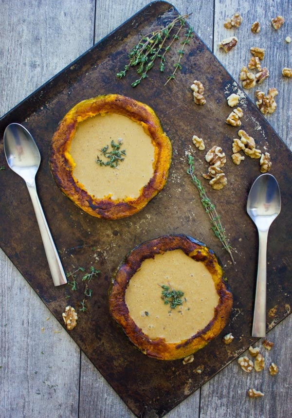 overhead shot of vegan squash soup with walnuts served in two halved squashes