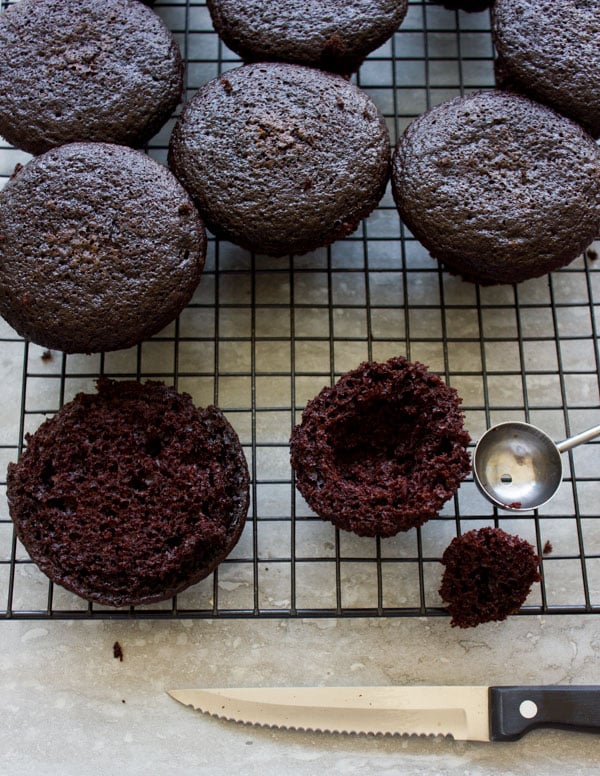 half a chocolate muffin being hollowed out to be filled with cream