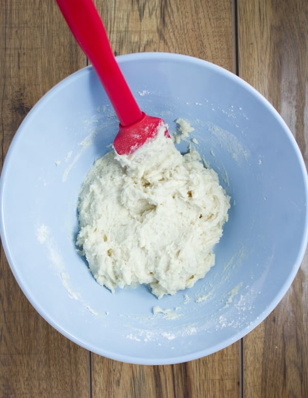vanilla cake batter being folded with a silicon spatula