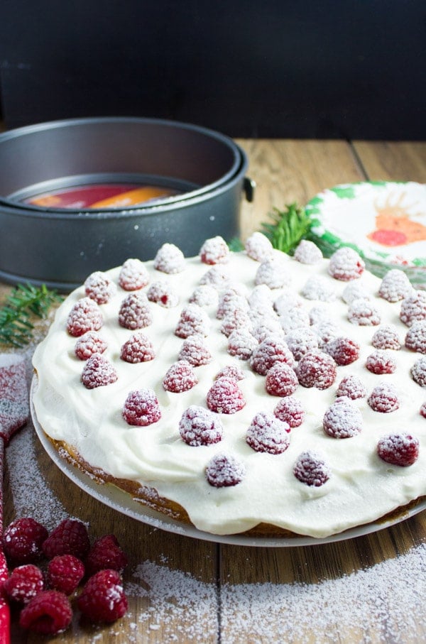 Fluffy White Raspberry Holiday Cake with vanilla whipped cream and fresh sugar-dusted raspberries 