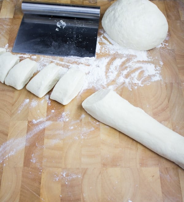 dough for homemade dinner rolls being shaped into a log before cutting