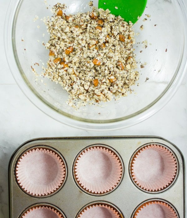 a bowl of granola next to a lined muffins tin