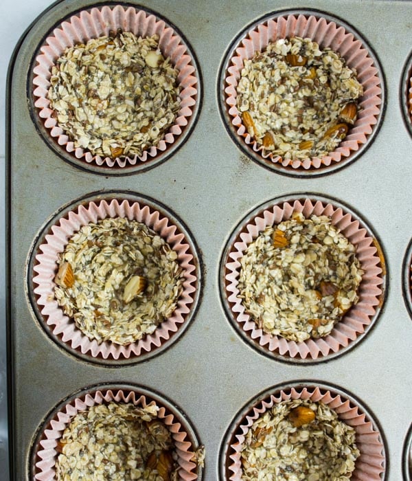 granola being pressed into muffin tins to make granola cups