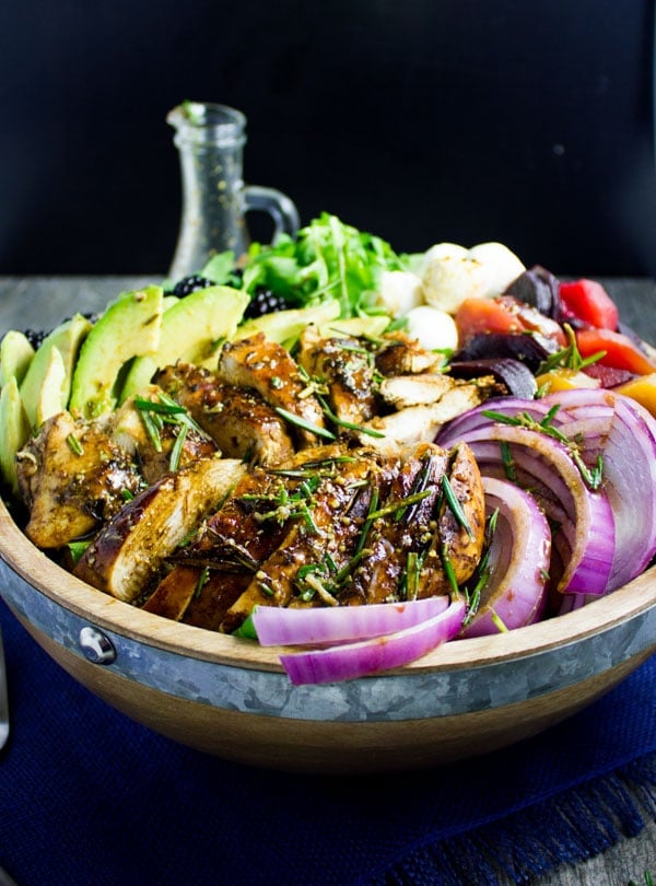 side view of a bowl of Italian Balsamic Chicken Salad with avocado and, red onions and blackberry dressing