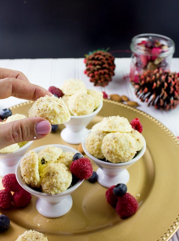 a hand holding an almond crunch Greek yogurt cheesecake bite