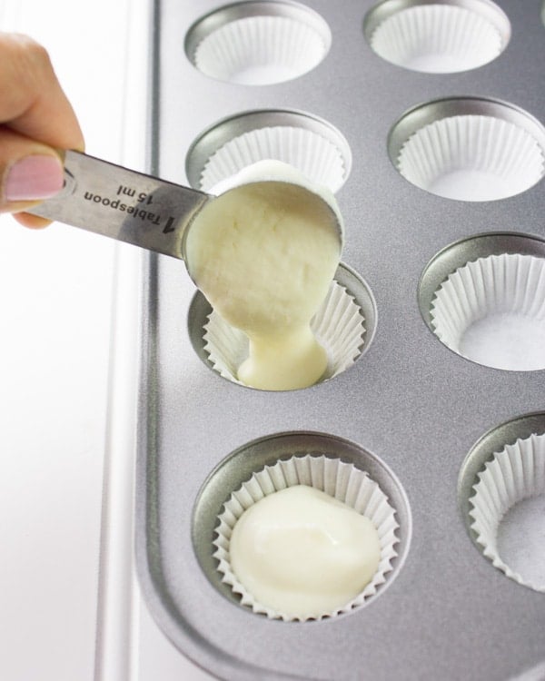 Greek yogurt filling being spooned into a lined muffin tin 