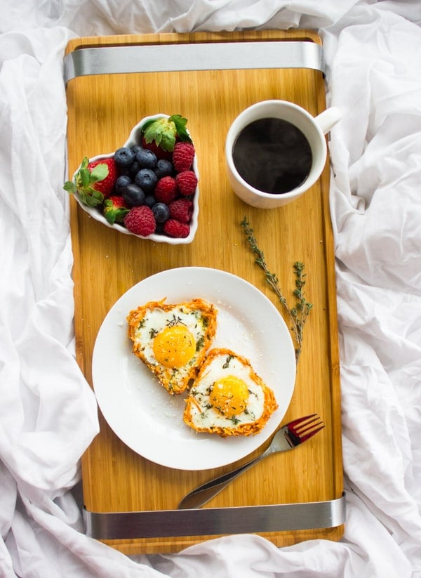 Baked Eggs in Sweet Potato Crusts served on a breakfast tray with a side of berries and a cup of coffee