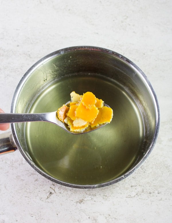orange peel being added to simple syrup in a pot