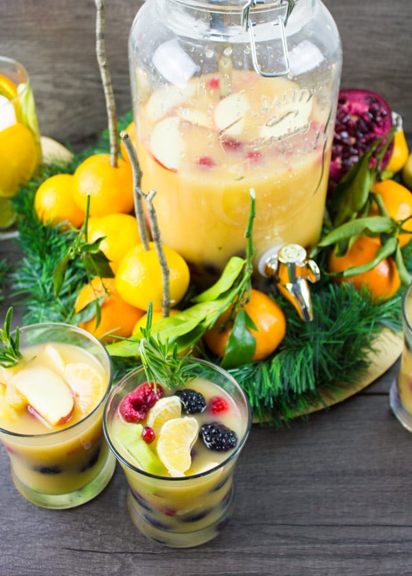 Fruity Non-Alcoholic Sangria with plenty of fruit served in glasses with a big mason jar of sangria in the back