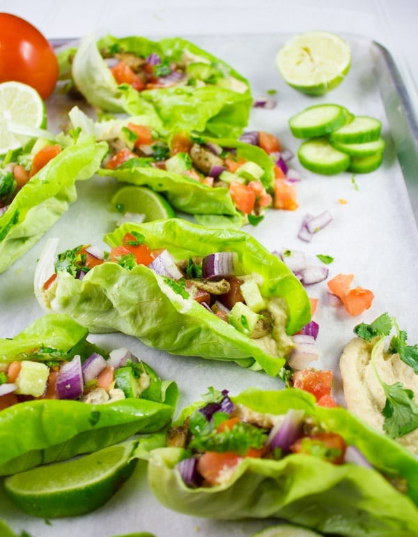 Chicken Shawarma served in crisp lettuce leaves arranged on a baking sheet with some cucumber slices and diced onions