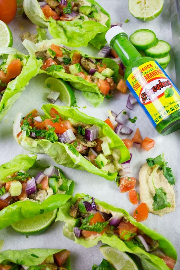 Chicken Shawarma in Lettuce Cups arranged on a sheet pan with a bottle of green chili sauce on the side