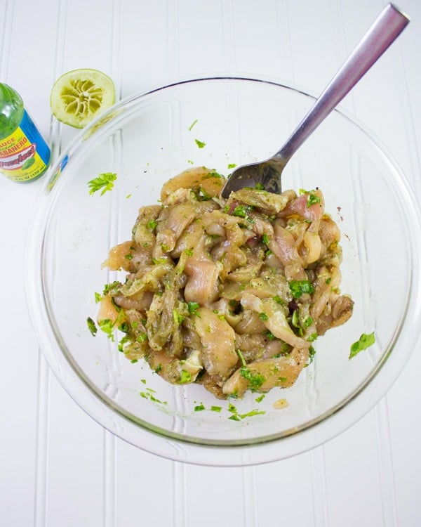 ingredients for chicken shawarma recipe being mixed in a glass bowl