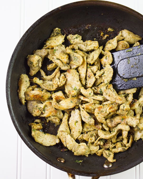 Chicken Shawarma in the process of being fried in a black skillet pan