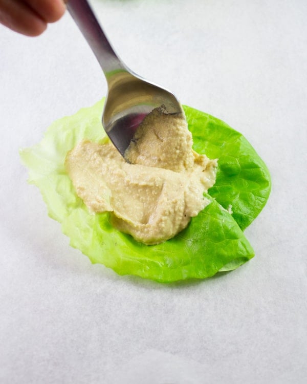 lettuce leave with a dollop of hummus as the base for a chicken lettuce wrap