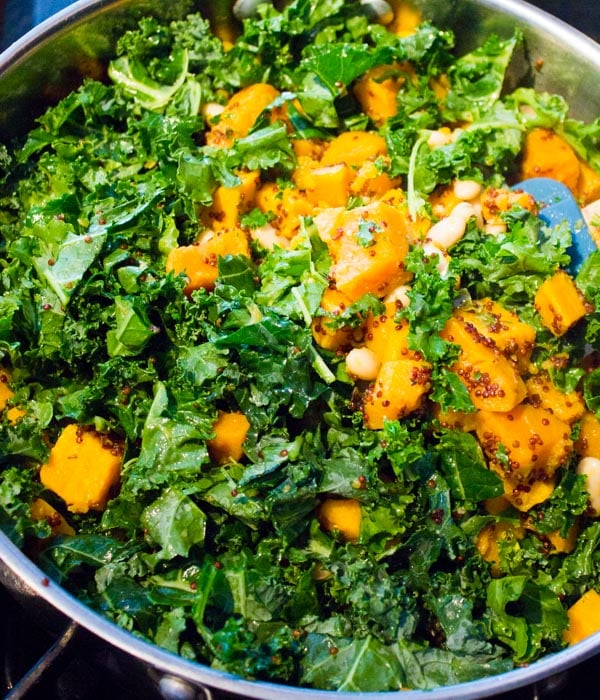 kale and sweet potato chunks sprinkled with quinoa, sauteeing in a saucepan