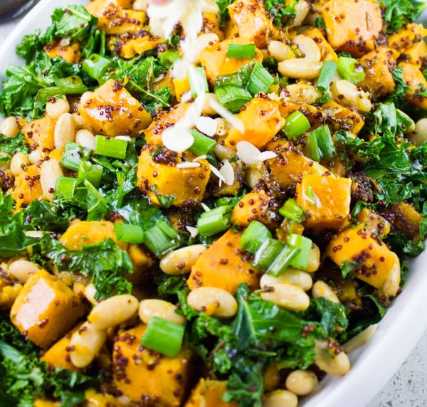 almonds being scattered on top of sweet potato salad