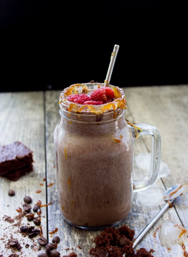 caramel-drizzled Espresso Brownie Chocolate Smoothie served in a mason jar glass with a straw and fresh raspberries sprinkled on top