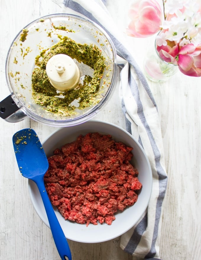 Ground beef mixture in a bowl and the spices and herbs in a another bowl