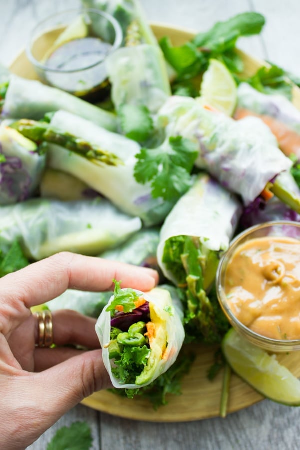 a hand holding a Rice Paper Rolls with one bite taken out the front to reveal the veggie filling