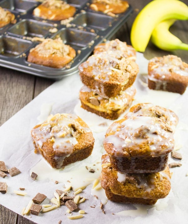 Banana Bread Muffins stacked over each other with a banana at the back and some cream cheese icing on the side 