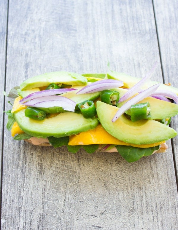 half a ciabatta bun topped with mango, avocado slices, red onion rings and fresh cilantro