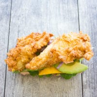 open ciabatta sandwich topped with crispy fried chicken, mango and avocado slices