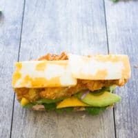 an open sandwich topped with fried chicken fingers, mango and marbled cheddar cheese