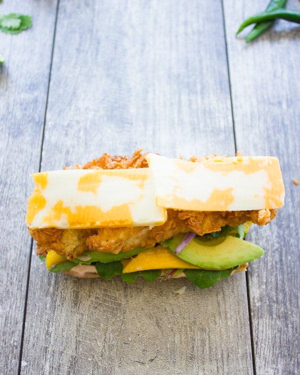 an open sandwich topped with fried chicken fingers, mango and marbled cheddar cheese