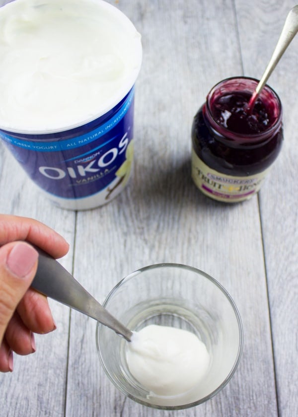 vanilla yogurt being added to a small glass bowl