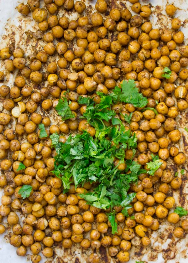 seasoned canned chickpeas on a parchment paper lined tray ready to be roasted