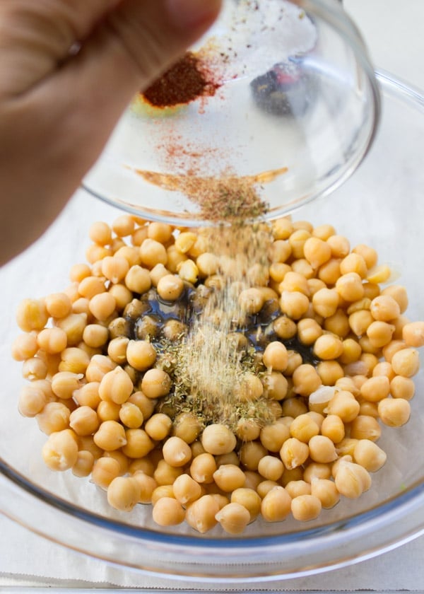canned chickpeas being tossed with seasoning to make roasted chickpeas