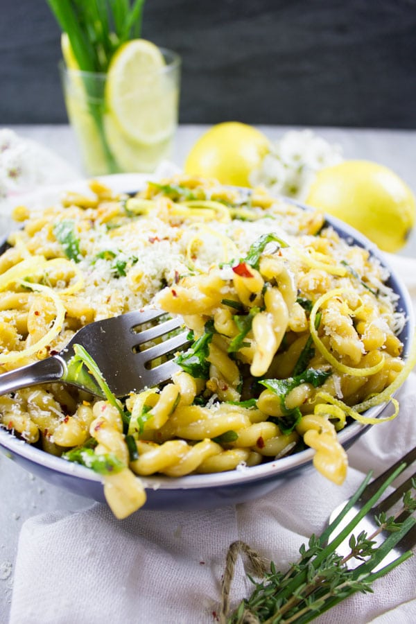 side view of a bowl of Easy Garlic Lemon Pasta with arugula, lemon zest and parmesan