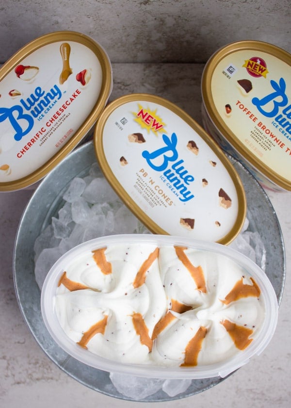 An opened box of ice cream showing the peanut butter swirl on the vanilla ice cream over an ice bucket.