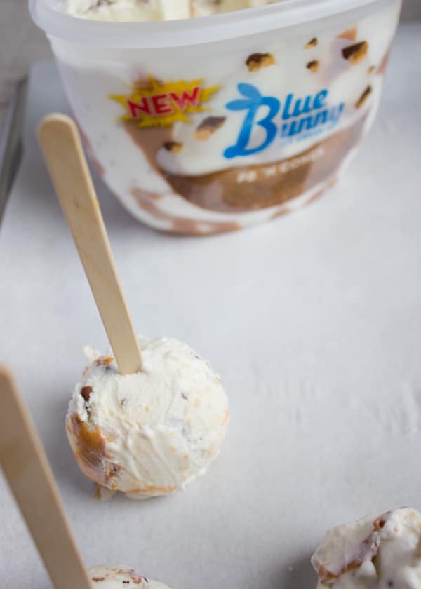 Placing a stick over the middle of each ice cream scoop.