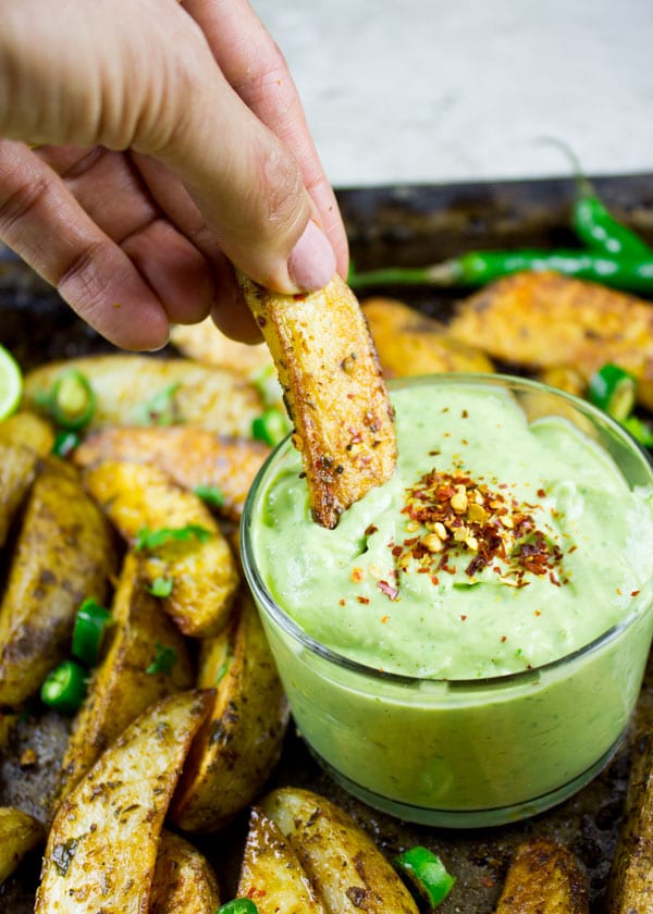 Perfect Baked Potato Wedge being dipped into a small dish with avocado crema