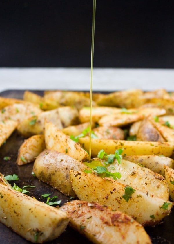 Potato Wedges being drizzled with olive oil before baking